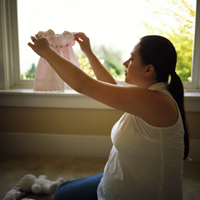 Woman sitting near window holding up a toddler's dress